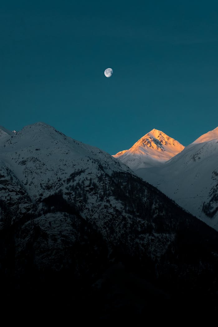 services-img Breathtaking view of a snow-capped mountain peak under the moonlight at twilight.